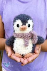 stuffed penguin toy held in person's hands thumbnail