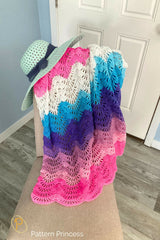 colorful baby blanket draped over a chair with a summer hat on top thumbnail
