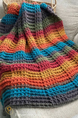 colorful crocheted throw blanket in colorful self-striping yarn draped over a couch thumbnail