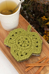crocheted leaf-shaped coasters in autumn colors on a wooden board next to a cup of tea thumbnail
