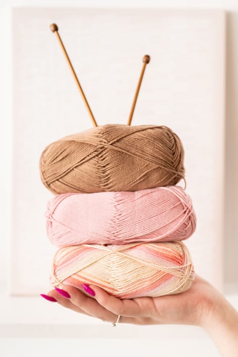 Woman comparing yarn swatches at home table