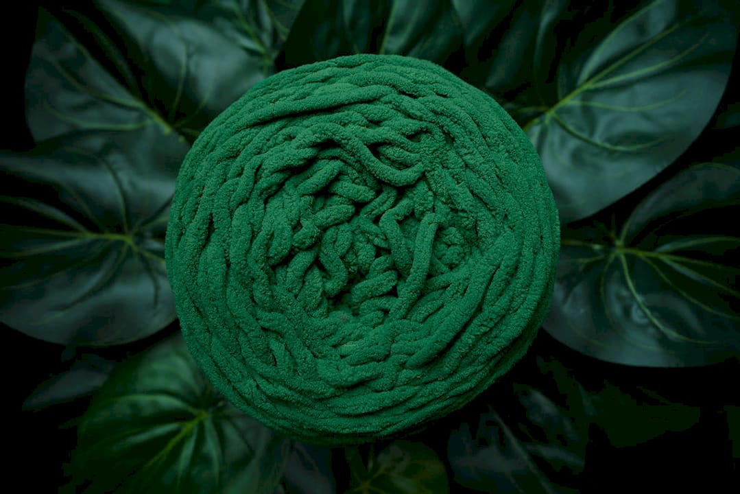 Black woman crocheting velvet yarn scarf indoors