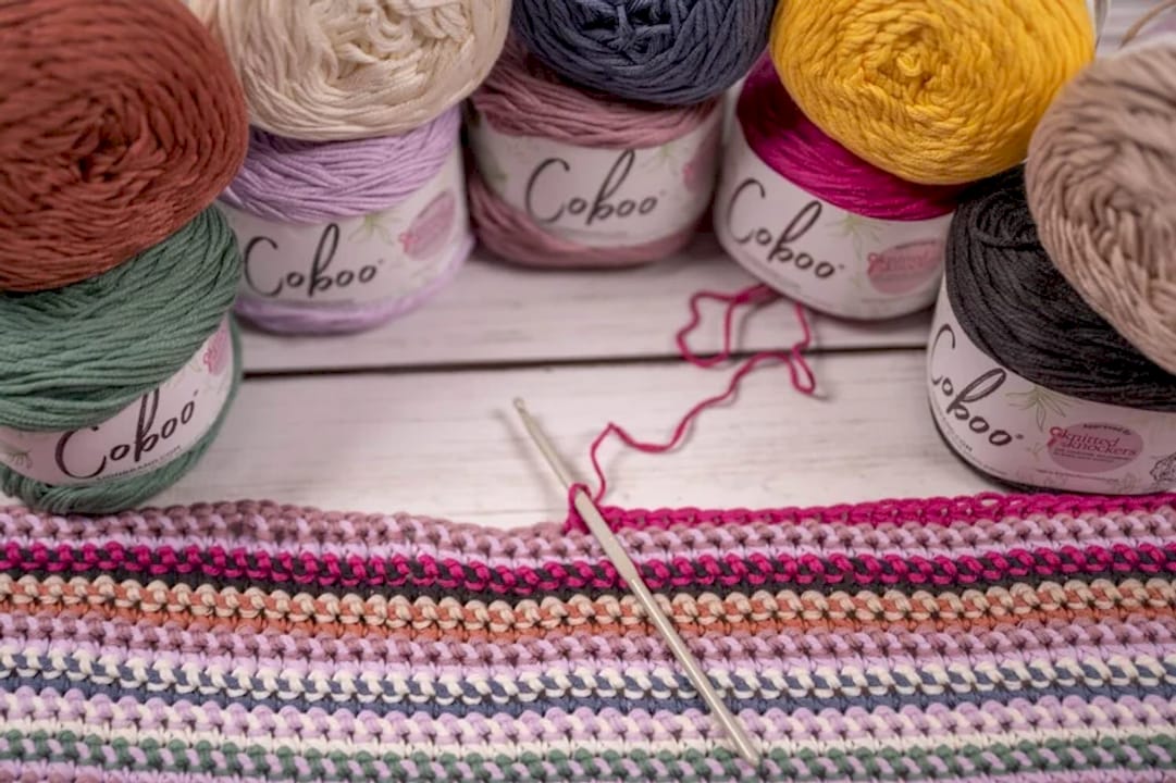 Woman crocheting colorful blanket indoors