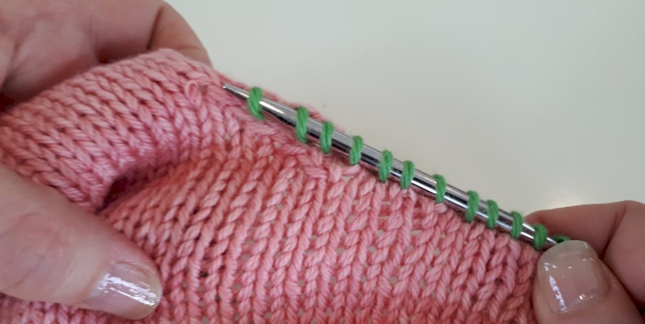 Woman picking up stitches on knitted swatch